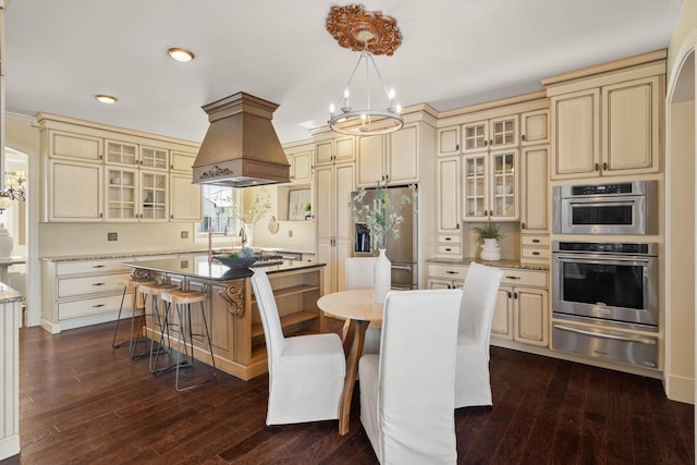 3207 Rivington Dr, Columbia, MO 65203 - kitchen with cream cabinetry, appliances with stainless steel finishes, premium range hood, a warming drawer, and a chandelier