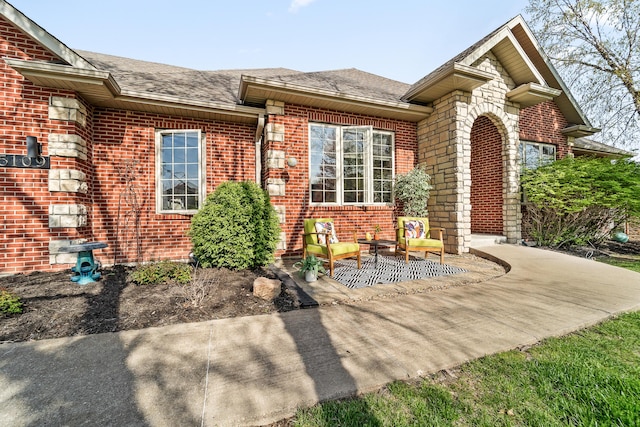 5109 Newbury Way, Columbia, MO 65203 - doorway to property featuring a shingled roof, a patio area, and brick siding