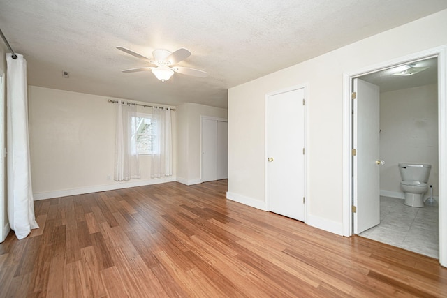 unfurnished bedroom featuring light wood-style flooring, baseboards, and a textured ceiling