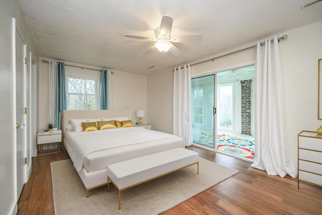 bedroom featuring a ceiling fan, access to outside, wood finished floors, and visible vents