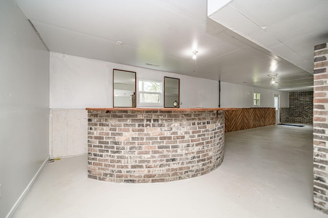bar with concrete floors, wooden walls, and brick wall