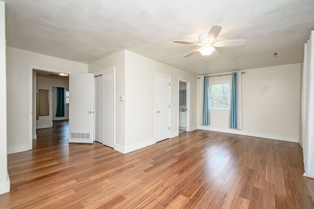interior space featuring light wood finished floors, a textured ceiling, baseboards, visible vents, and a ceiling fan