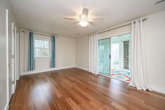 empty room featuring visible vents, baseboards, wood finished floors, and ceiling fan