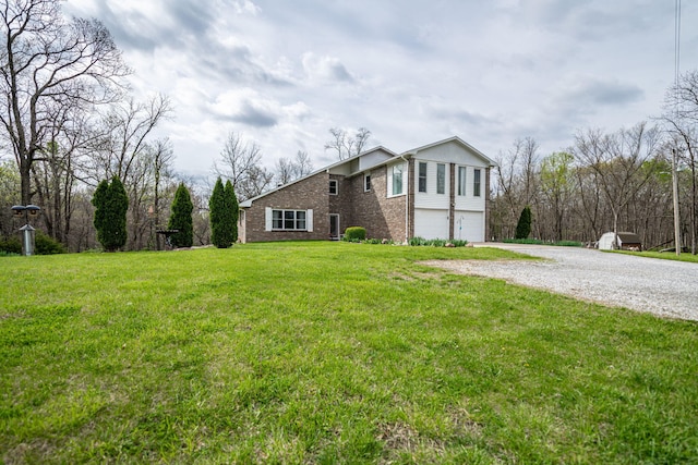 view of front of home with brick siding, an attached garage, driveway, and a front lawn
