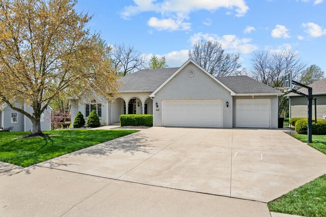 view of front of property with roof with shingles, a front lawn, driveway, an attached garage, and stucco siding