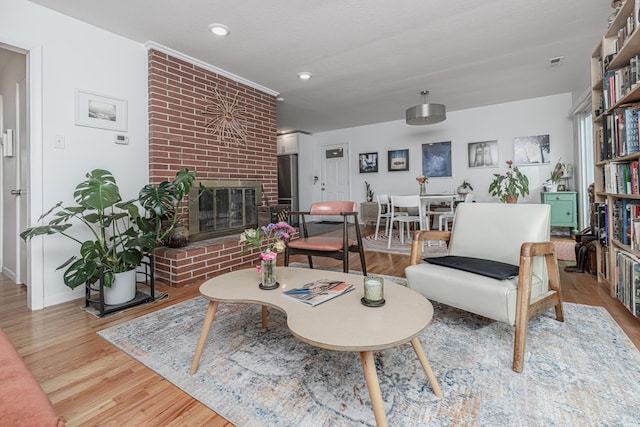 living room featuring wood finished floors, a brick fireplace, baseboards, and recessed lighting