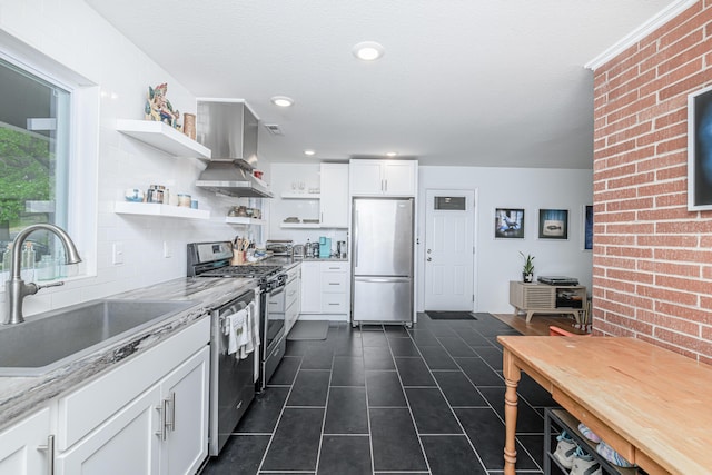 kitchen with stainless steel appliances, open shelves, a sink, wall chimney range hood, and white cabinetry