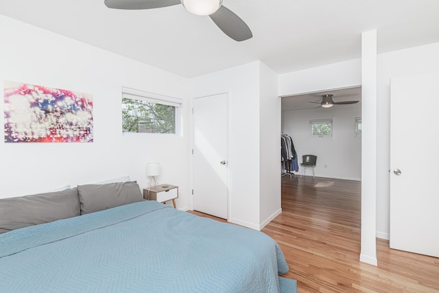 bedroom with light wood-type flooring, a ceiling fan, and baseboards