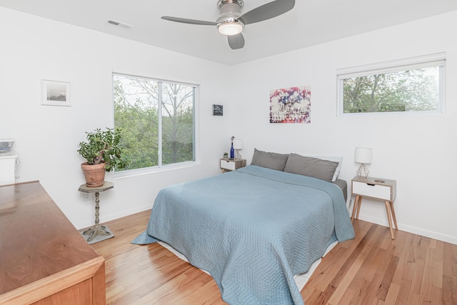 bedroom featuring light wood-type flooring, multiple windows, and baseboards