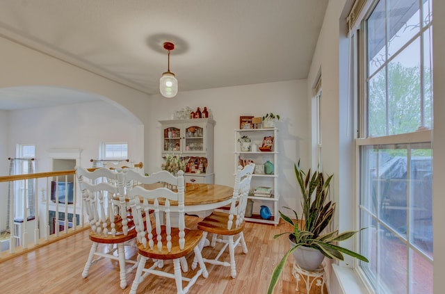 dining room with arched walkways and light wood-type flooring