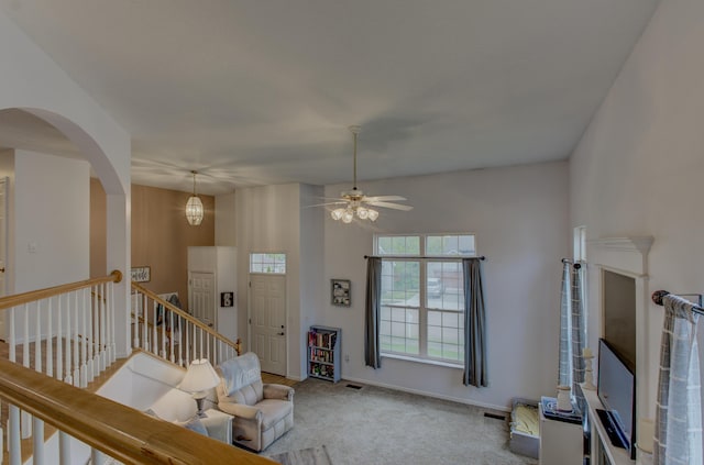 living room featuring ceiling fan, carpet floors, arched walkways, baseboards, and visible vents