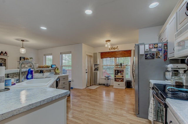 kitchen featuring plenty of natural light, a sink, stainless steel electric range, and light countertops