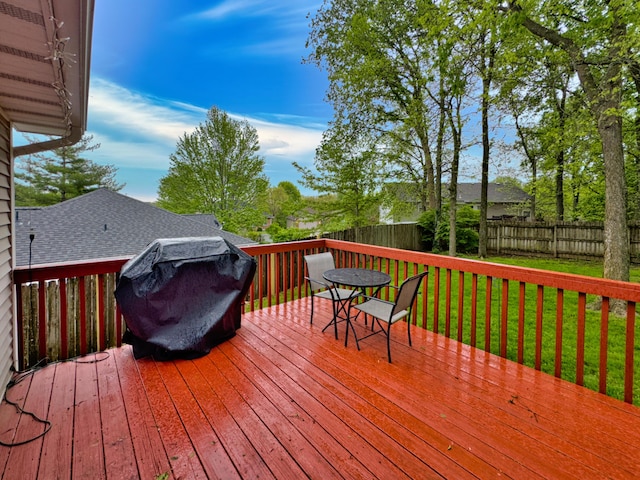 deck with area for grilling, a lawn, outdoor dining area, and a fenced backyard