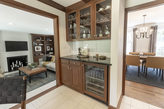 indoor dry bar with wine cooler, a chandelier, decorative backsplash, and light tile patterned floors