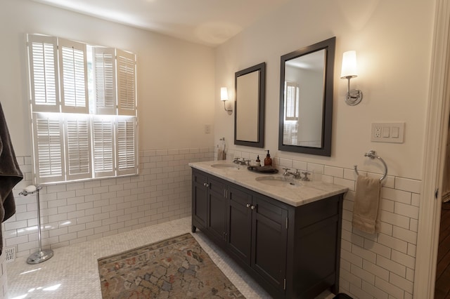 full bath featuring tile walls, a wainscoted wall, double vanity, and tile patterned floors