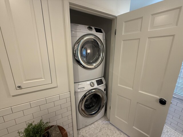 clothes washing area featuring stacked washer / drying machine and light tile patterned floors