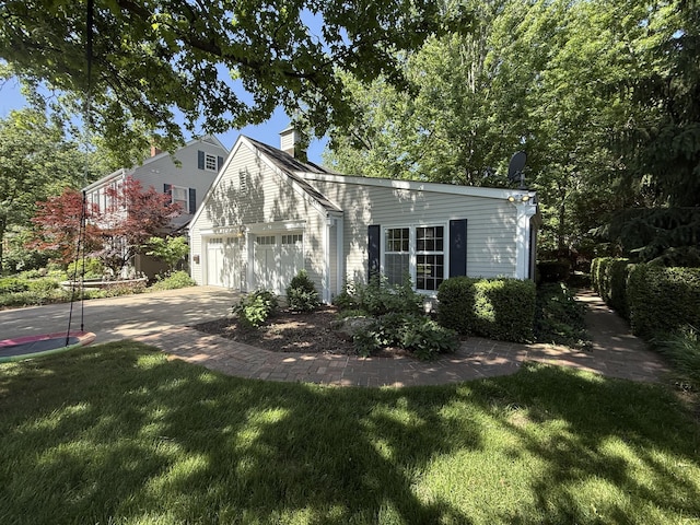 view of front facade with a chimney, driveway, a front yard, and a garage