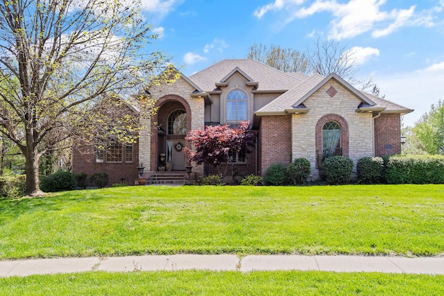 view of front of home featuring stone siding, a front lawn, and a shingled roof
