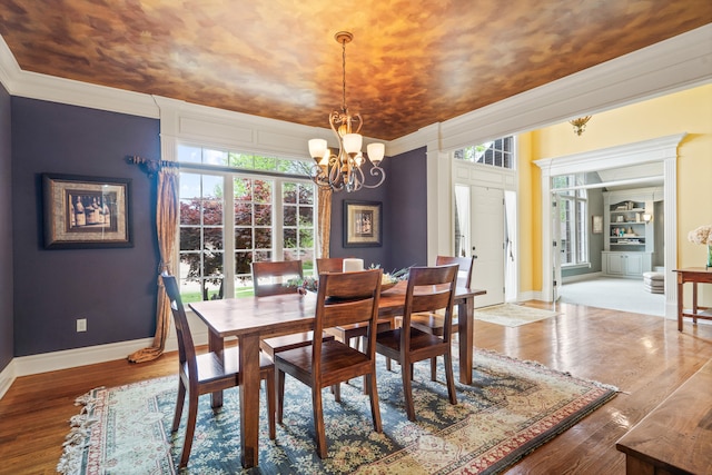 dining room featuring baseboards, wood finished floors, a notable chandelier, and ornamental molding