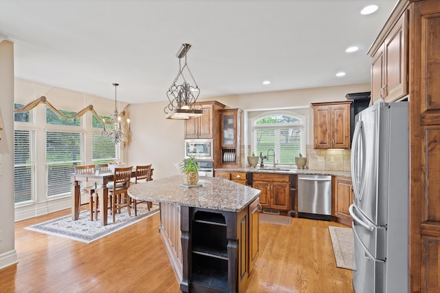 kitchen with brown cabinetry, open shelves, stainless steel appliances, and a sink