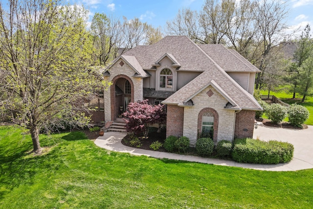 view of front of home with stone siding, a front yard, and a shingled roof