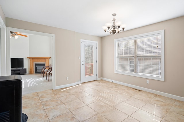 unfurnished dining area with light tile patterned flooring, a glass covered fireplace, visible vents, and baseboards