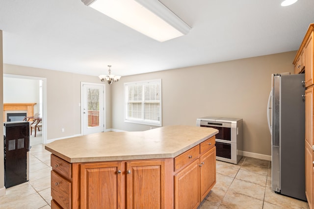 kitchen featuring light countertops, freestanding refrigerator, a center island, and light tile patterned floors