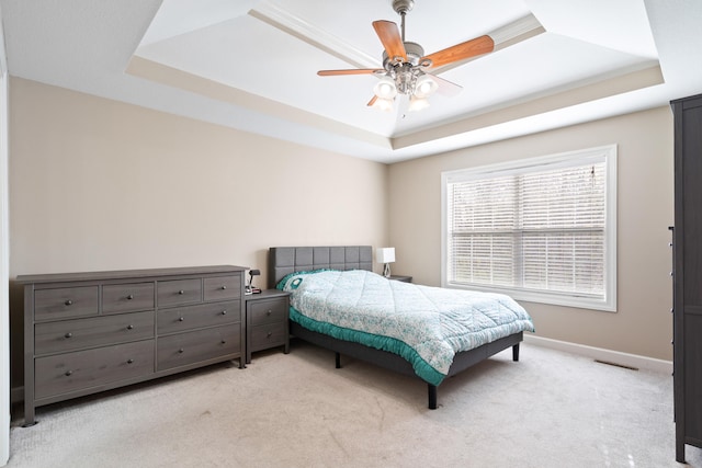 bedroom with light carpet, visible vents, baseboards, a ceiling fan, and a raised ceiling