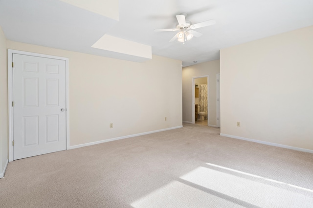 unfurnished bedroom featuring baseboards, a ceiling fan, light colored carpet, and connected bathroom