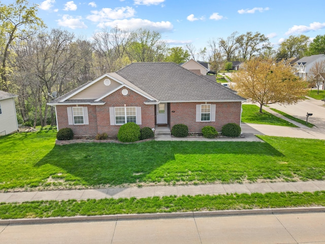 ranch-style house featuring brick siding, roof with shingles, and a front lawn