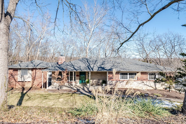 single story home with a chimney, a front lawn, brick siding, and a porch