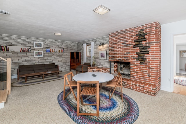 carpeted dining space featuring a brick fireplace and visible vents