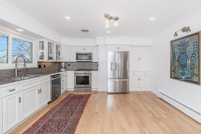 kitchen featuring a baseboard radiator, a sink, glass insert cabinets, stainless steel appliances, and light wood-style flooring