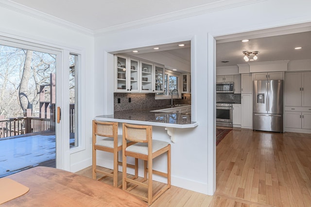 kitchen featuring gray cabinets, glass insert cabinets, decorative backsplash, crown molding, and appliances with stainless steel finishes