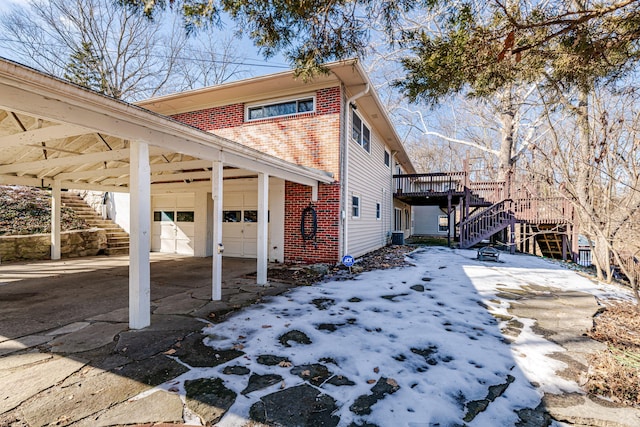 view of property exterior featuring stairway, driveway, a deck, an attached garage, and brick siding
