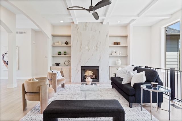 living area featuring arched walkways, wood finished floors, built in shelves, and visible vents
