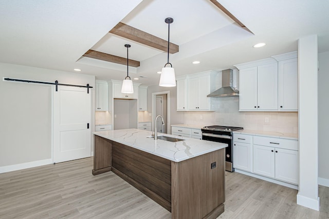 709 Sagemoor Dr, Columbia, MO 65201 - kitchen featuring wall chimney range hood, stainless steel range with gas cooktop, a barn door, a sink, and light wood-style flooring