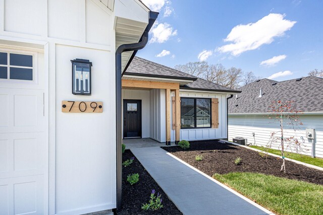 709 Sagemoor Dr, Columbia, MO 65201 - view of exterior entry featuring central air condition unit, board and batten siding, and a shingled roof