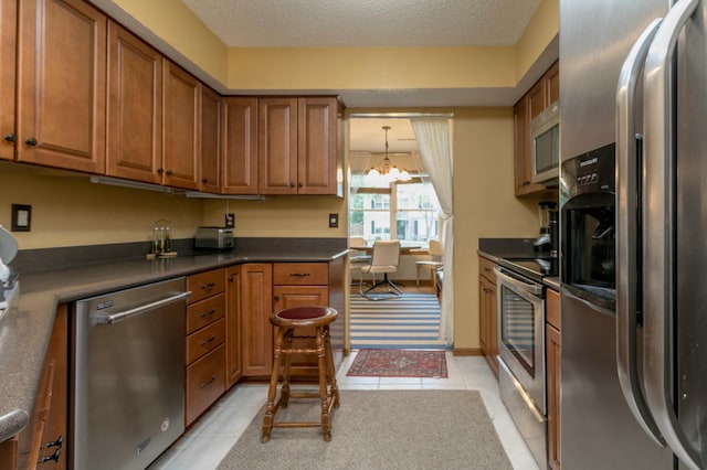 3701 Churchill Dr, Columbia, MO 65201 - kitchen featuring brown cabinetry, light tile patterned floors, dark countertops, and appliances with stainless steel finishes