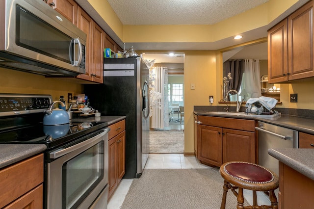 3701 Churchill Dr, Columbia, MO 65201 - kitchen with appliances with stainless steel finishes, dark countertops, brown cabinets, and a sink