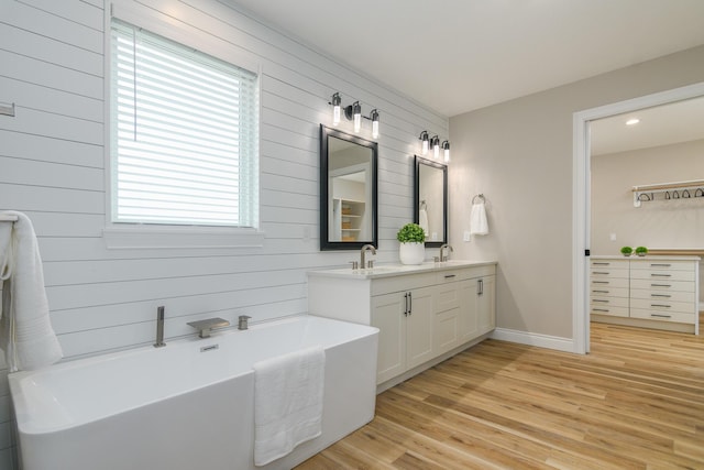6301 Crooked Switch Ct, Columbia, MO 65201 - full bathroom featuring double vanity, wooden walls, a freestanding bath, wood finished floors, and baseboards
