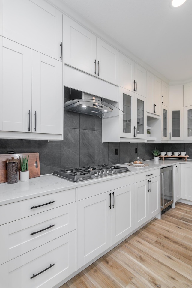 6301 Crooked Switch Ct, Columbia, MO 65201 - kitchen with beverage cooler, backsplash, white cabinets, stainless steel gas cooktop, and wall chimney range hood