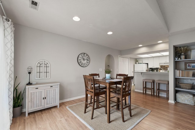 dining area featuring visible vents, arched walkways, light wood finished floors, and recessed lighting