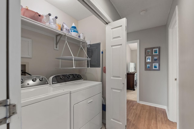 laundry room with laundry area, electric panel, washing machine and dryer, baseboards, and light wood finished floors