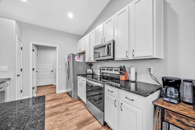 1103 Baseball Dr, Foristell, MO 63384 - kitchen with light wood-type flooring, white cabinetry, dark stone countertops, appliances with stainless steel finishes, and vaulted ceiling