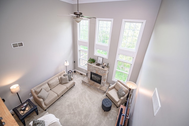 living area featuring carpet flooring, a fireplace, a ceiling fan, visible vents, and baseboards