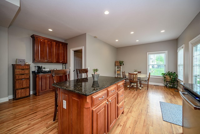 kitchen featuring recessed lighting, dark stone counters, dishwasher, light wood finished floors, and baseboards