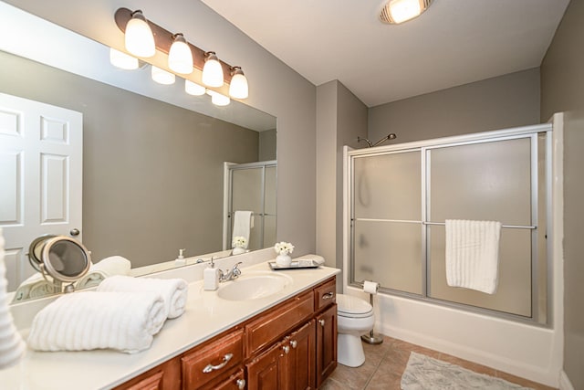 bathroom featuring tile patterned floors, toilet, enclosed tub / shower combo, and vanity