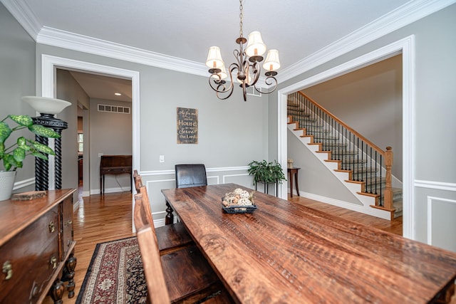 dining area with an inviting chandelier, stairs, ornamental molding, light wood-type flooring, and visible vents