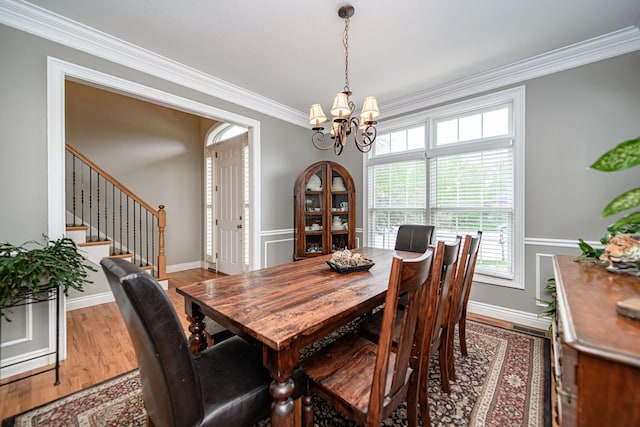 dining area featuring wood finished floors, a chandelier, plenty of natural light, and crown molding